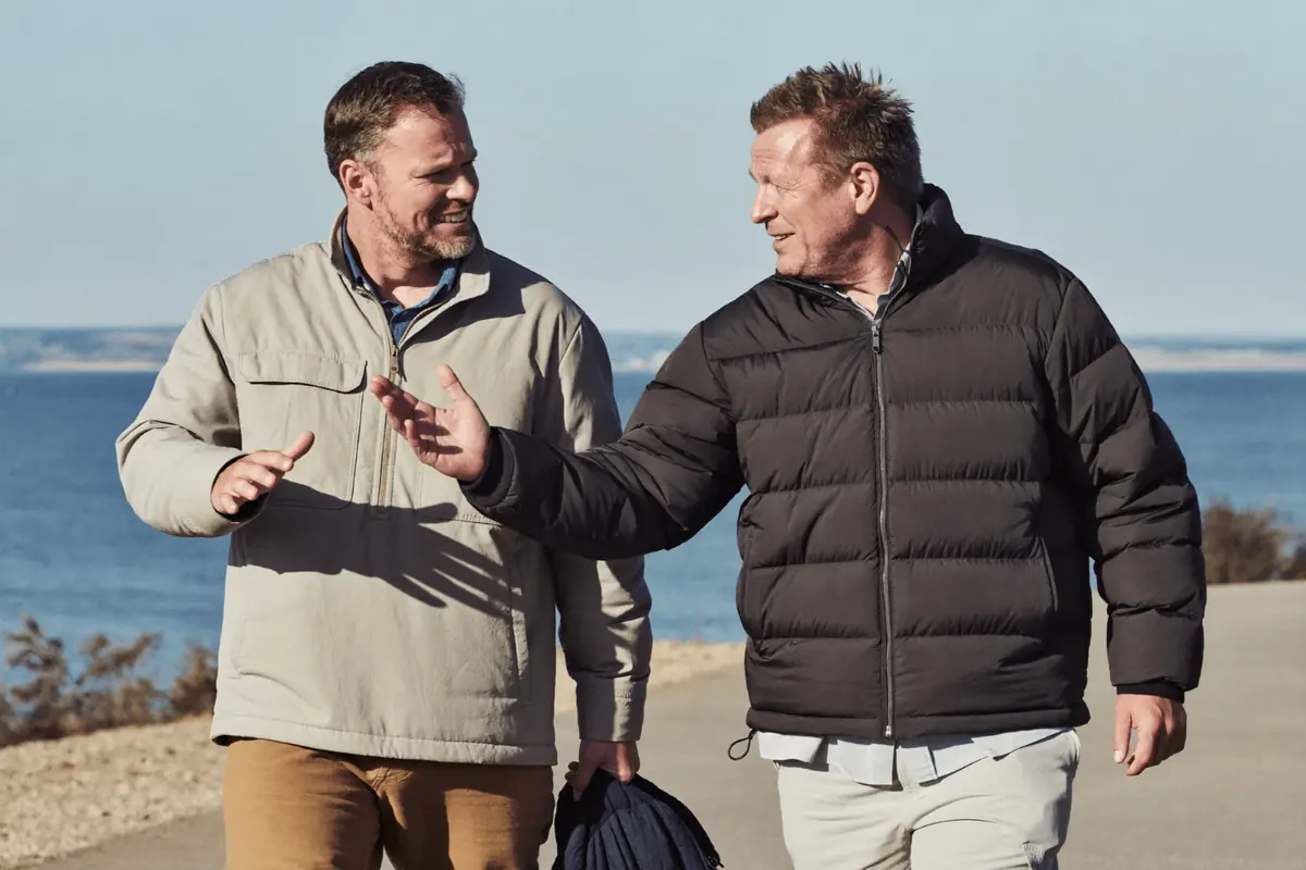 Two men talk as they walk a coastal path