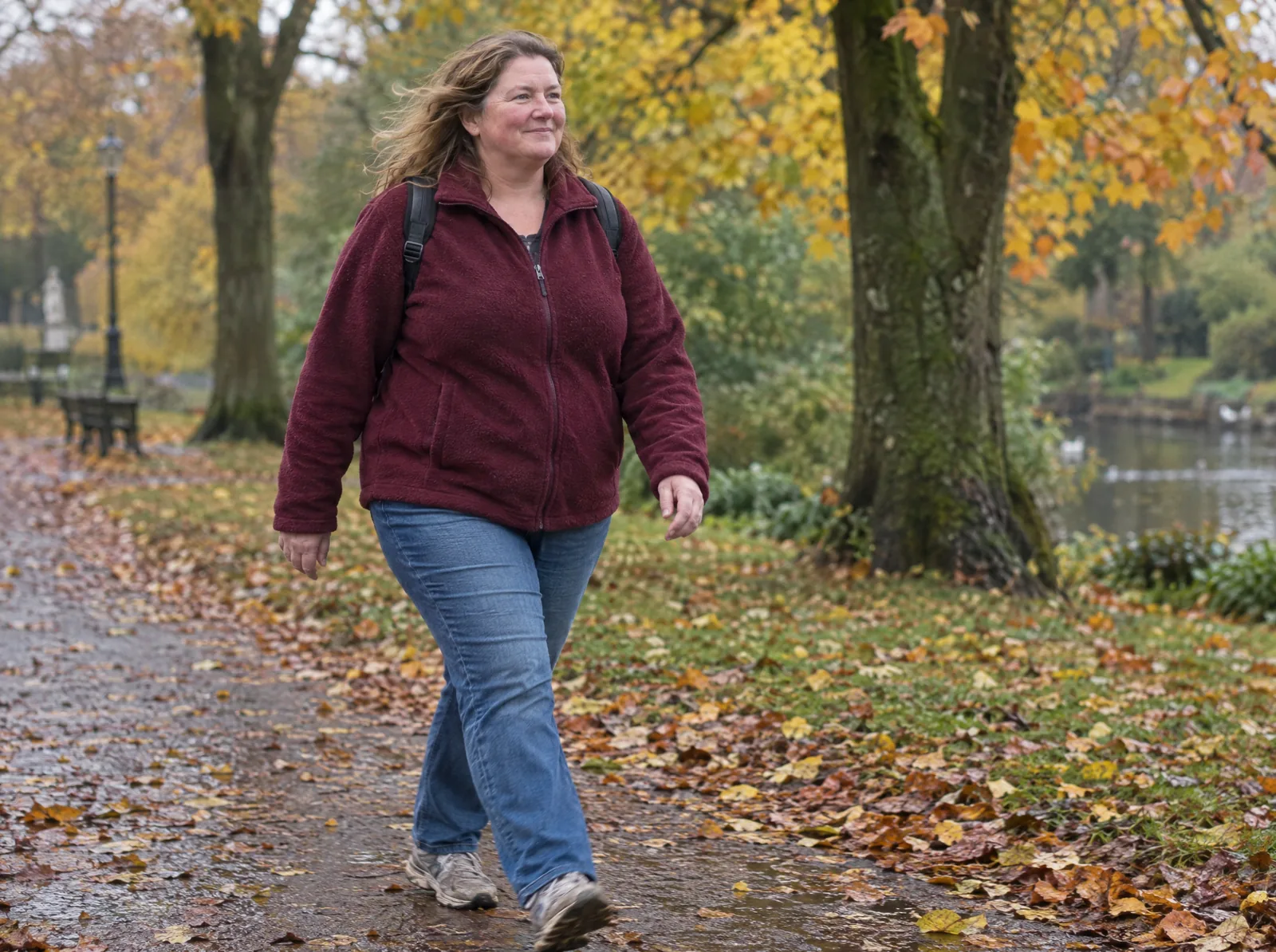 A woman walks at an easy pace through a park in autumn